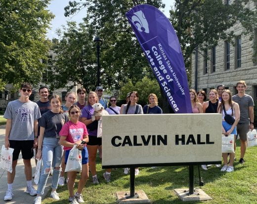 Students posed and smiling, standing near the Calvin Hall sign