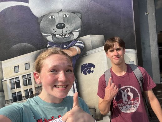 Two K-State students in front of a mural featuring Willie the Wildcat, in Aggieville, Manhattan, Kansas