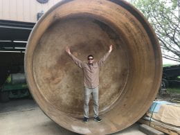 Ted Harris stands in a very large circular vat to demonstrate its size.