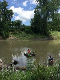Three people, two on the river bank and one in a boat, take measurements on the Cottonwood River.